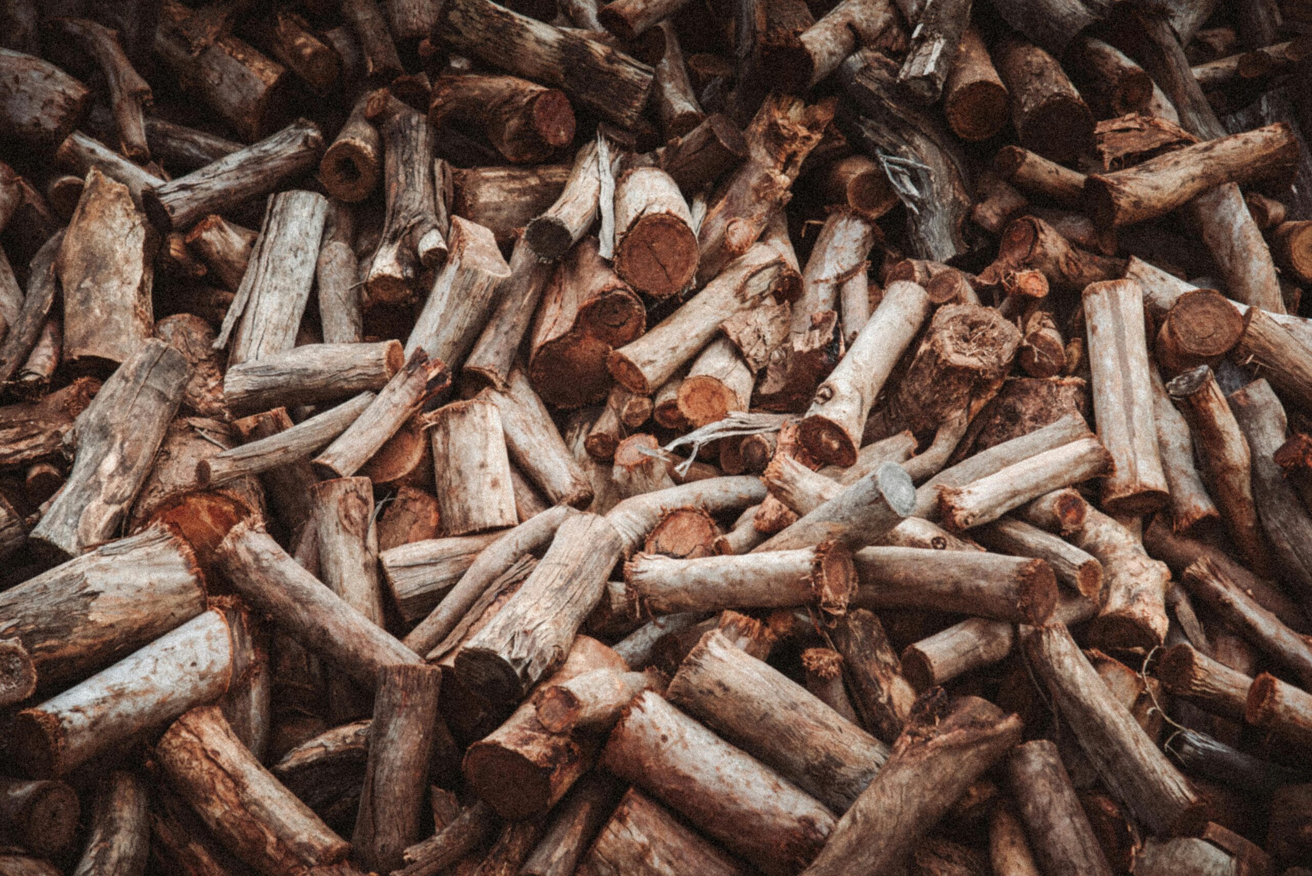 A large pile of cut firewood logs with a rustic texture, ideal for winter heating.